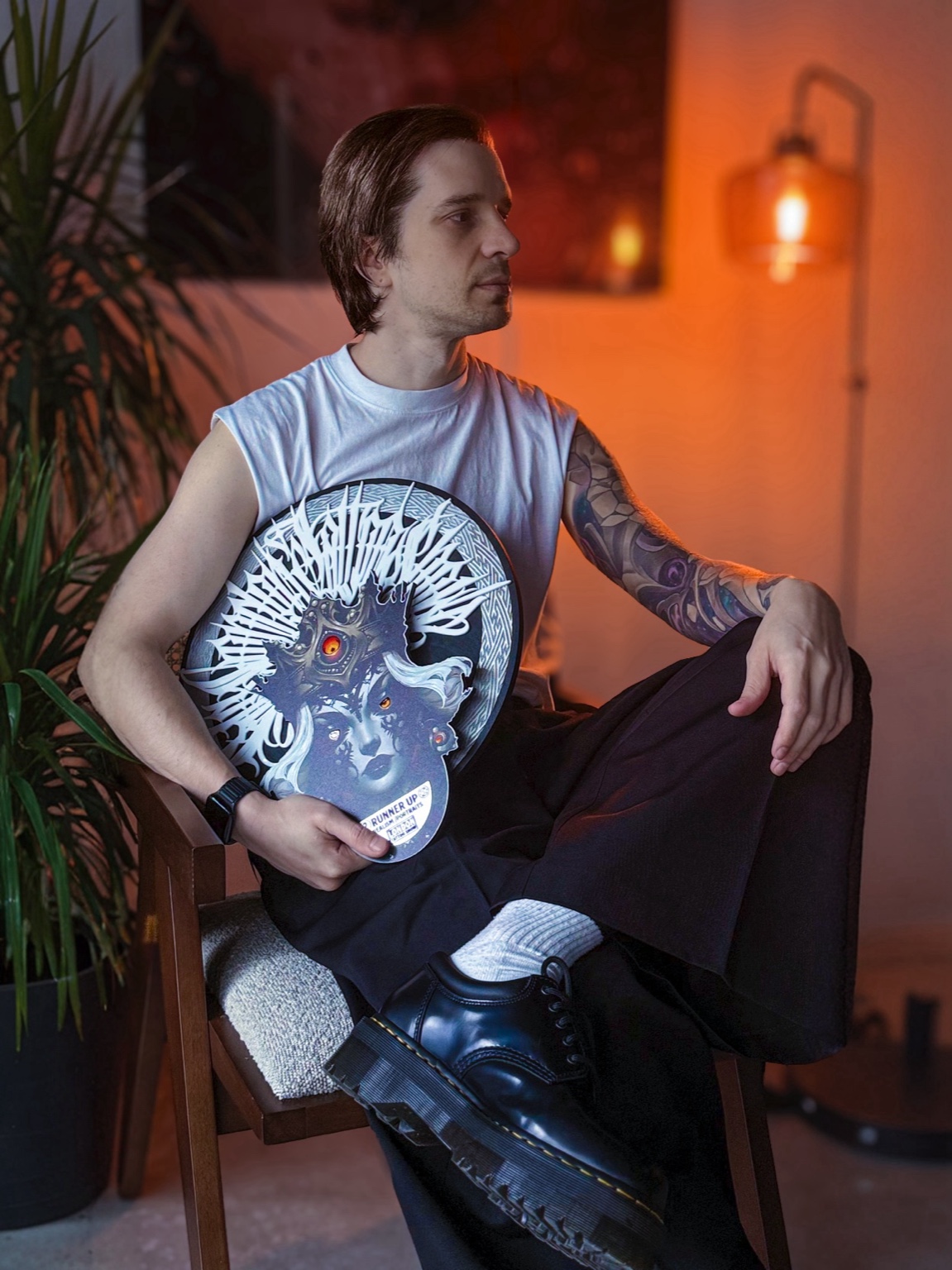 Vladimir Vishar holding a tattoo convention award, with a colour realism sleeve visible